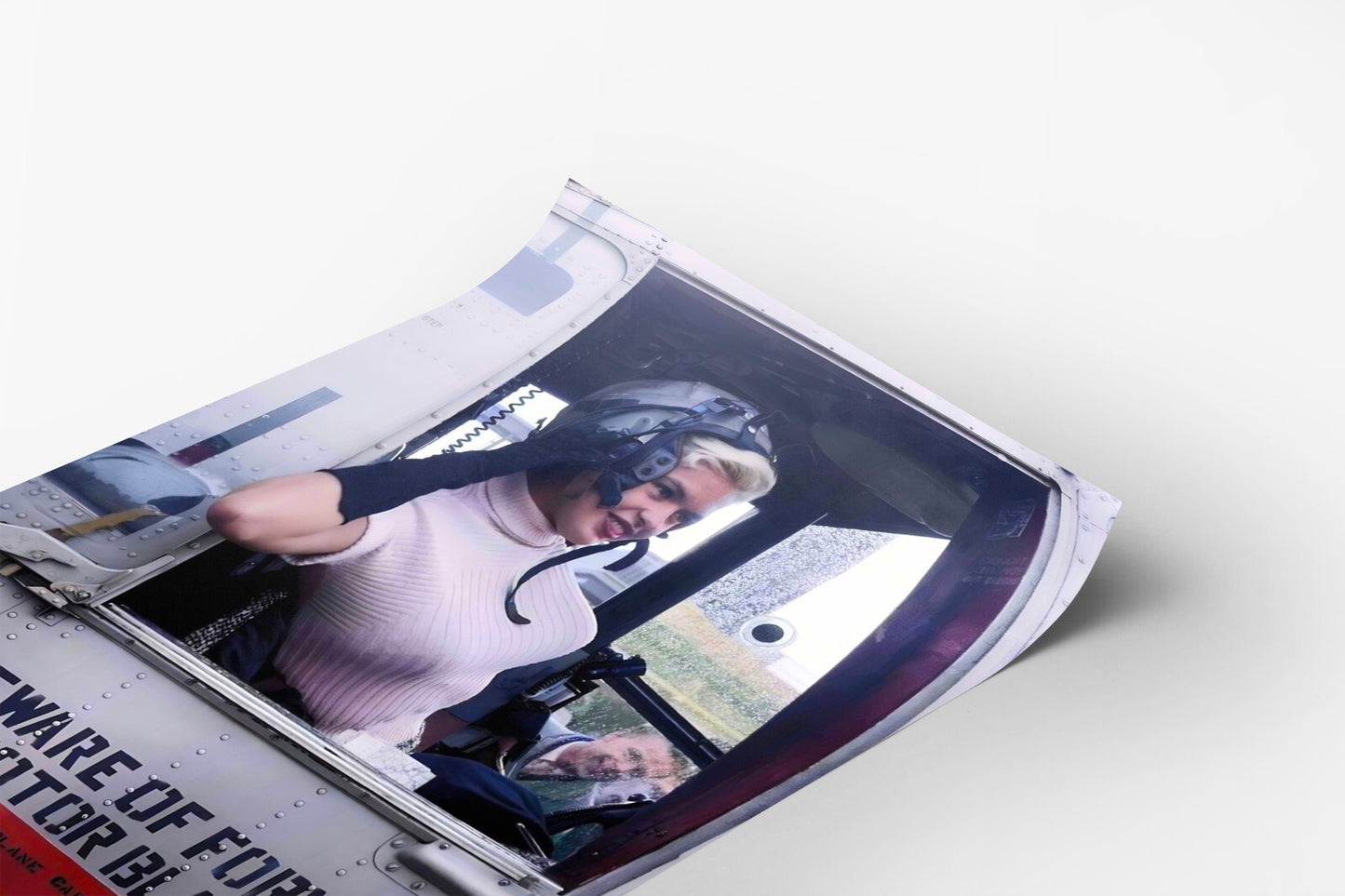 A woman wearing a helmet is sitting in the cockpit of an aircraft, looking out the window.