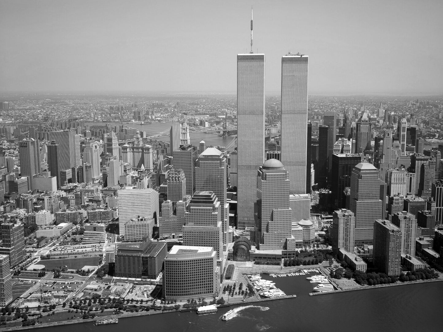 A black and white aerial view of the New York City skyline, featuring the iconic twin towers of the World Trade Center.