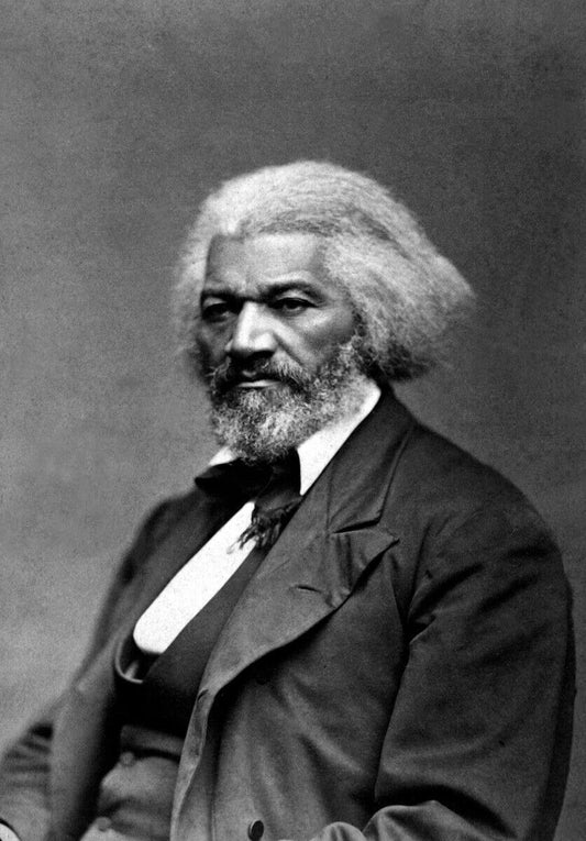 A black and white portrait of a man with a long white beard, wearing a suit and tie, looking directly at the camera with a serious expression.