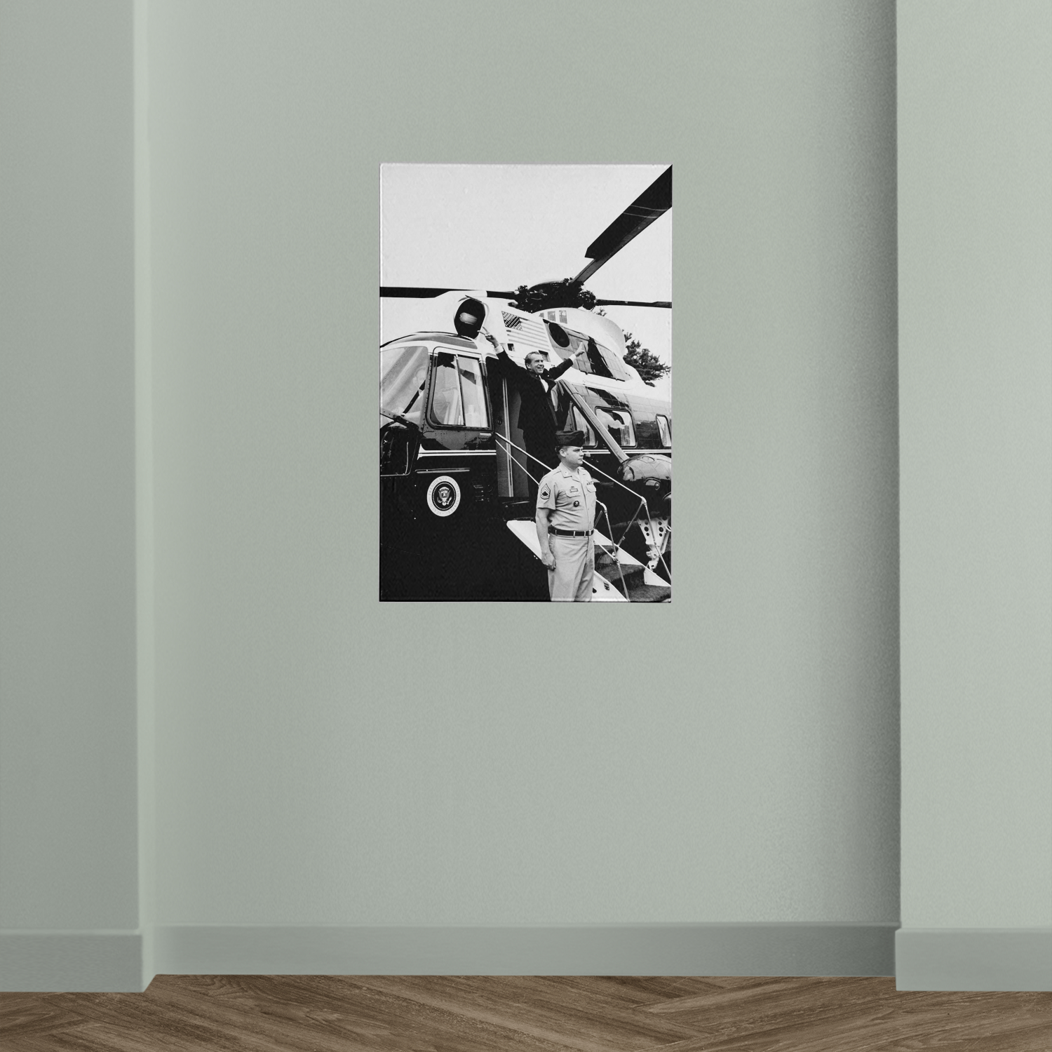 A black and white photograph of a helicopter with a person standing next to it, mounted on a wall.