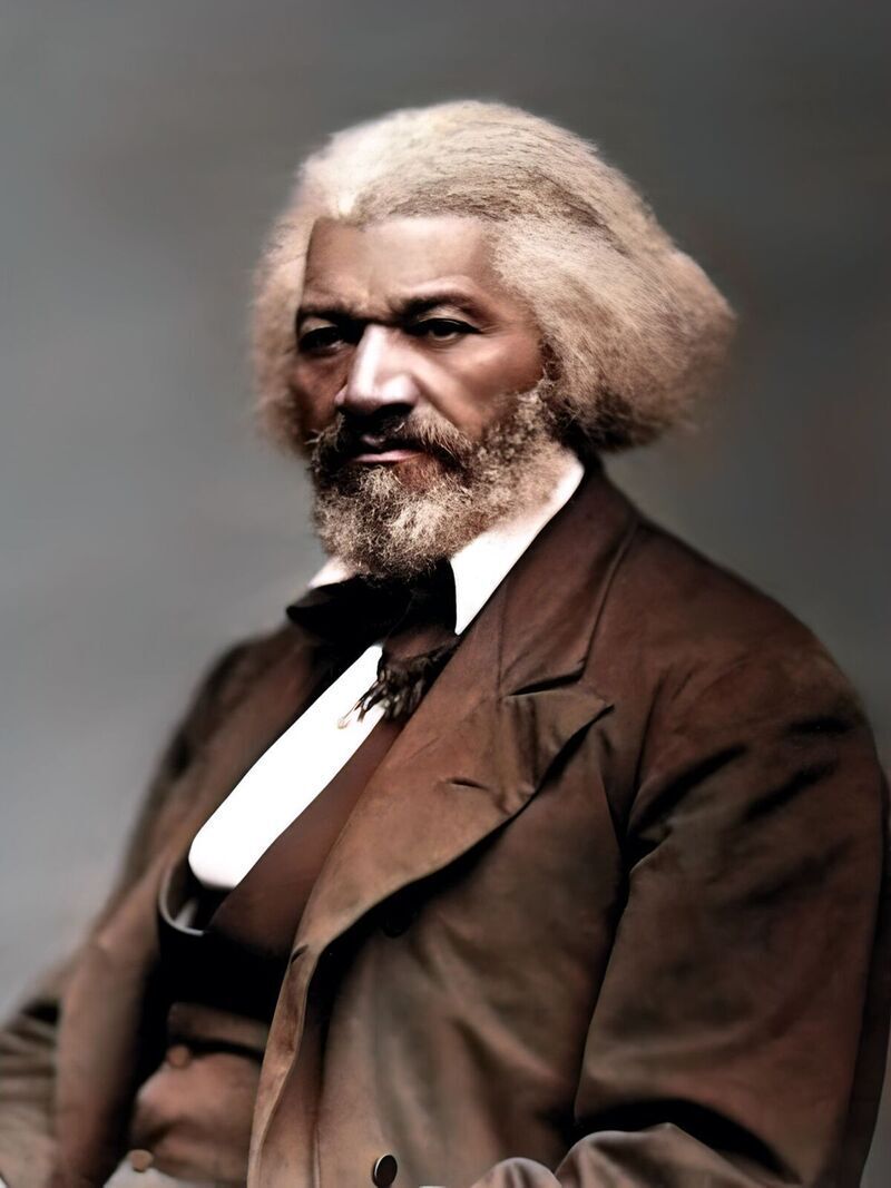 A portrait of a man with a long white beard wearing a brown suit and tie, looking directly at the camera with a serious expression.