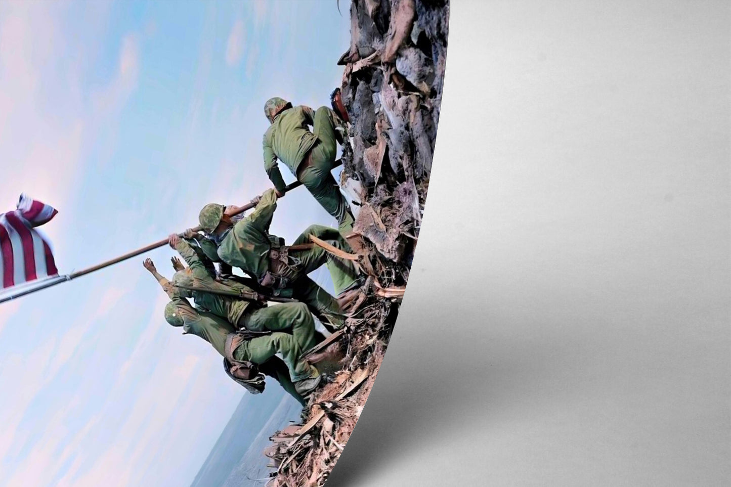 A group of soldiers in green uniforms are working together to pull up a flag on a rocky hillside, with an American flag visible in the background.