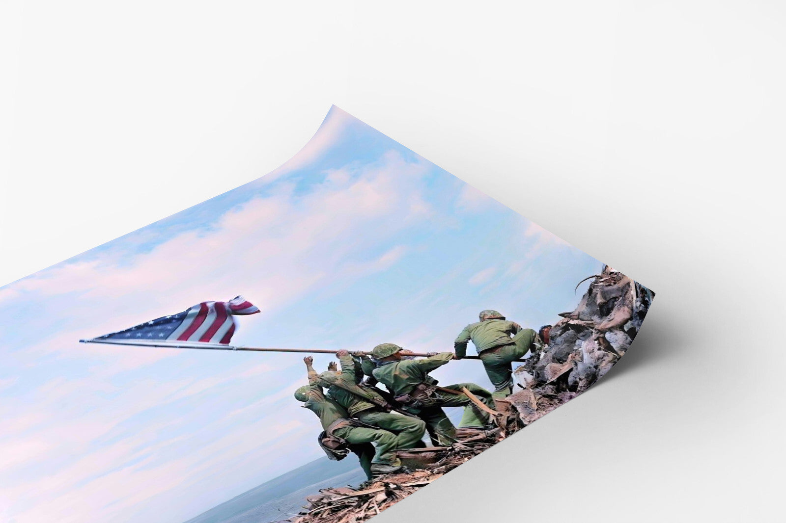 A group of soldiers in green uniforms are working together to raise an American flag on a rocky hill, with a clear blue sky in the background.