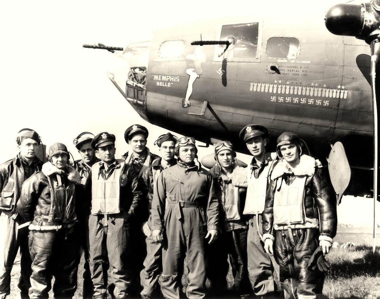 A group of men in military uniforms standing in front of a World War II-era bomber aircraft.