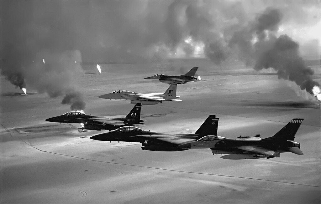 A group of military jets flying in formation, with smoke and fire visible in the background.